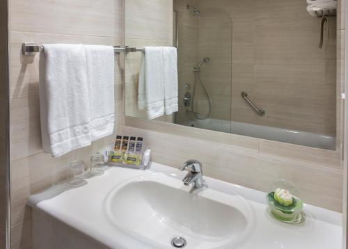 y baño con lavabo, espejo y toallas. en Avanti Hotel, en Pafos