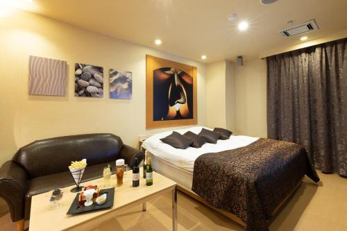 a bedroom with a bed and a table with a couch at ホテル マイン 岐阜 in Ginan