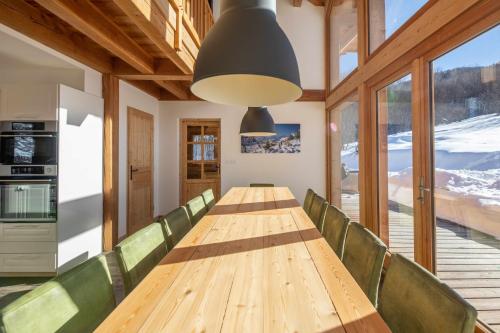 uma sala de jantar com uma mesa longa e cadeiras verdes em Maison Puy Saint Vincent em Puy-Saint-Vincent