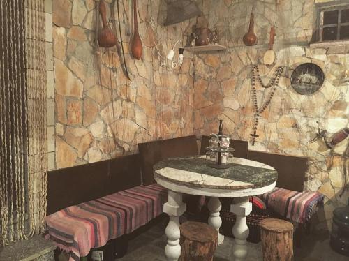 a table and bench in a room with a stone wall at Apartments Kolak in Rogoznica
