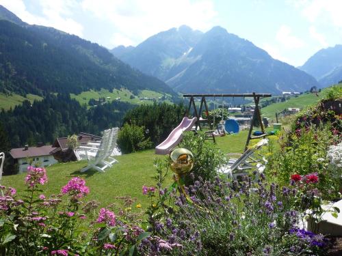 a playground with a slide in a field with mountains at Ferienwohnung Vier Jahreszeiten in Hirschegg