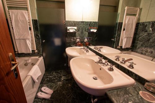 a bathroom with two sinks and a tub at Albergo Le Due Corti in Como