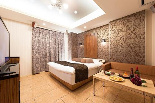 a bedroom with a bed and a table in a room at ホテル マイン 岐阜 in Ginan