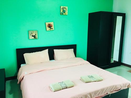1 dormitorio verde con 1 cama grande y 2 almohadas en The Rich Home, en Nakhon Ratchasima