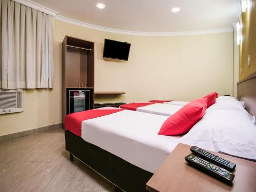 a hotel room with a bed with red and white pillows at Hotel Villa Rica in Rio de Janeiro