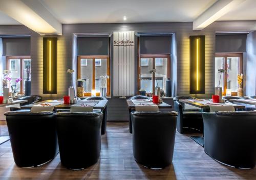 ein Restaurant mit schwarzen Stühlen, Tischen und Fenstern in der Unterkunft SL'otel - Das Stadthotel in Bernburg