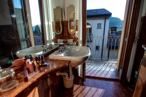 une salle de bains avec deux lavabos et une vue sur un balcon. dans l'établissement Albergo Le Due Corti, à Côme