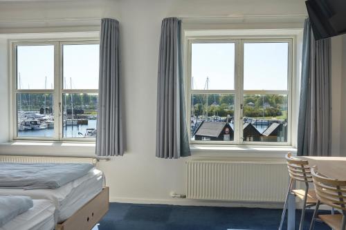 1 dormitorio con ventanas, 1 cama, mesa y sillas en BB-Hotel Aarhus Havnehotellet, en Aarhus