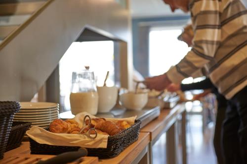 a person preparing food in a kitchen with a table with bread at BB-Hotel Aarhus Havnehotellet in Aarhus