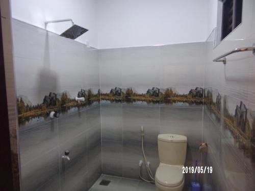 a bathroom with a toilet and a mural on the wall at Baywings Rooms in Arugam Bay