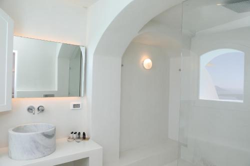 a white bathroom with a sink and a mirror at Panorama Suites in Fira