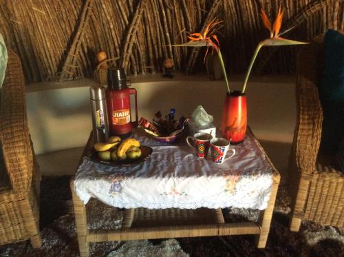 a table with a vase and a bowl of fruit at Swazi Dreams. (Nqabaneni Eco-Volunteering.) in Usutu