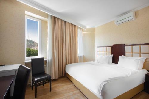 a hotel room with a bed and a desk and a window at GTM Kapan in Tbilisi City