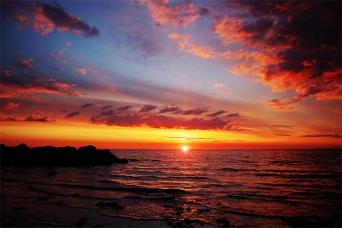 a sunset over the ocean with the sun setting at Vanilla Sky Apartments in Sillamäe