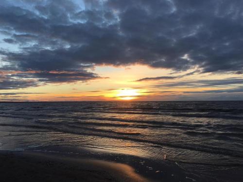 a sunset on the beach with the ocean at Vanilla Sky Apartments in Sillamäe