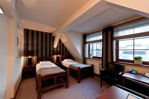 a hotel room with two beds and a desk at Hotel Tumski in Płock