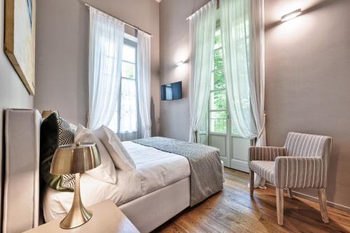 a bedroom with a bed and a chair and a window at Palazzo Del Carretto-Art Apartments and Guesthouse in Turin