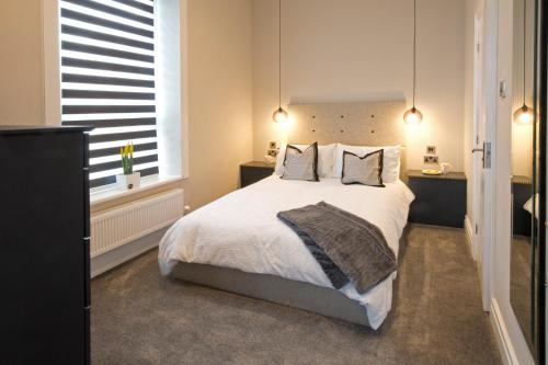 - une chambre dotée d'un grand lit avec des draps et des oreillers blancs dans l'établissement Blackbird Luxury Apartments Room 3, à Blackpool