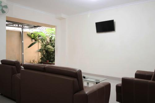 a waiting room with chairs and a tv on a wall at RedDoorz at Andalas Asri Lampung in Bandar Lampung
