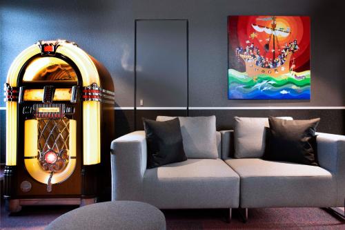 a living room with a couch and a large painting at Hotel Le Bugatti in Molsheim