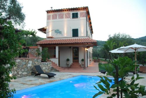 a villa with a swimming pool in front of a house at La Libellula- casale panoramico con piscina in Versilia in Massarosa