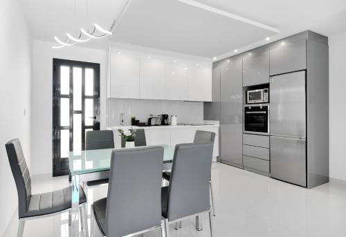 a white kitchen with a dining table and chairs at Apartment Diamante in Pilar de la Horadada