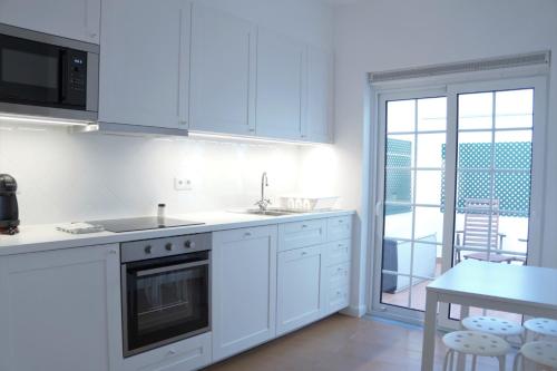 a kitchen with white cabinets and a table with a tableablish at Heritage Apartments in Funchal