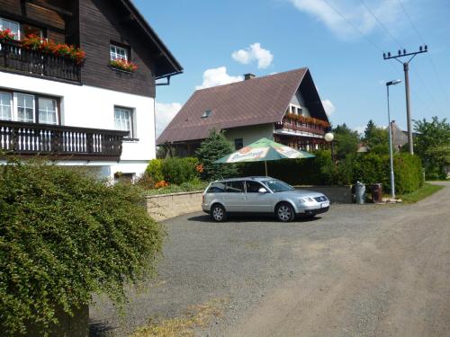 a car parked in front of a house with an umbrella at Pension Pugner in Vysoké nad Jizerou