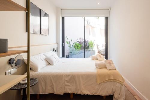 Schlafzimmer mit einem Bett mit weißer Bettwäsche und Kissen in der Unterkunft Petit Luxe Tobella Baixos in Terrassa