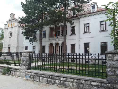 an old white house with a black fence at Apartments Mirković in Cetinje