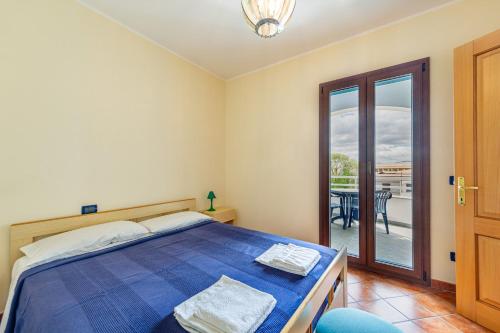 a bedroom with a bed and a balcony with a table at Le Residenze Del Porto in La Caletta