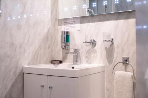 a white bathroom with a sink and a shower at Apartment 2, Pheonix Flats in Portree