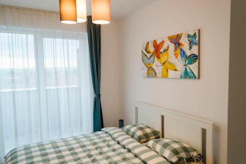 a bedroom with a bed and a window with a painting at Paul's place. New rooftop apartment in Downtown Sibiu in Sibiu