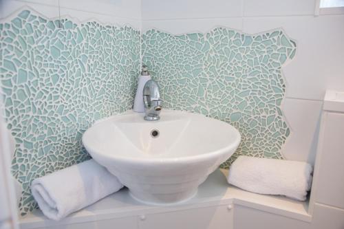 a white sink in a bathroom with green and white wallpaper at Bosanneth in Falmouth