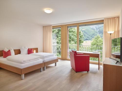 a living room with a bed and a red chair at Hotel Tödi in Linthal