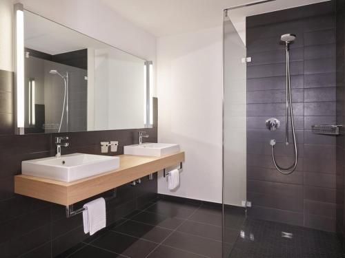 a bathroom with two sinks and a mirror and a shower at Hotel Tödi in Linthal