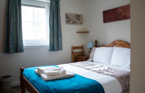 a bedroom with a bed with a blue blanket and a window at Apartment 2, Pheonix Flats in Portree