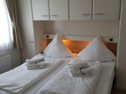 ヴェスターラントにあるSylter-Besserburg-App-16のベッド2台(白いシーツ、枕付)
