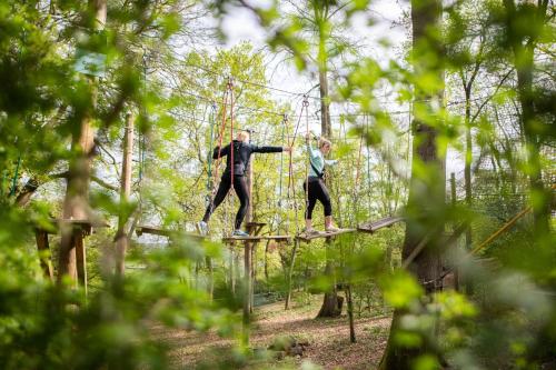 two people walking on a suspension bridge in the forest at Four Seasons Hotel Hampshire in Winchfield