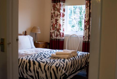 a bedroom with a zebra print bed with a window at Apartment 4 Pheonix Flats in Portree