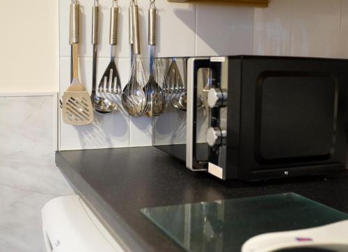 a kitchen counter with utensils hanging from a microwave at Apartment 4 Pheonix Flats in Portree