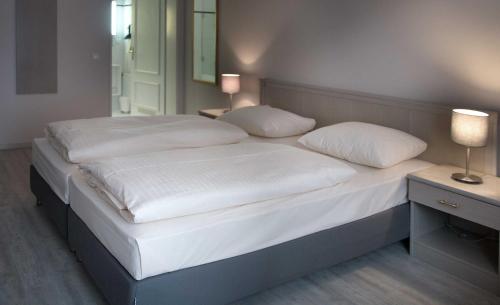 uma cama com lençóis brancos e almofadas num quarto em Hotel Deutsches Theater em Munique