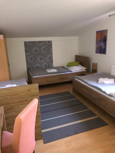 a room with two beds and a chair and a rug at Hotel Orlan in Bratislava
