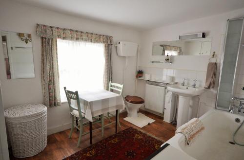 a bathroom with a sink and a toilet and a table at Grove Cottage in Yarmouth