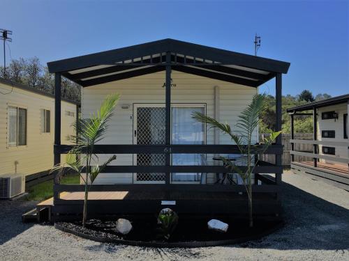 a tiny house with a black roof and two plants at Lakes Main Holiday Park in Lakes Entrance