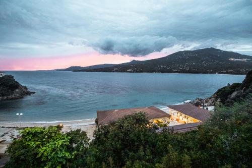 a view of a beach and the ocean at sunset at Hôtel Sampiero in Propriano