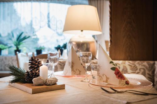 a table with a table centerpiece with a lamp and candles at Hotel Monte Cherz in Arabba