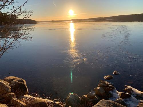 a sunset on a lake with rocks in the water at Strandstuga in Tämta