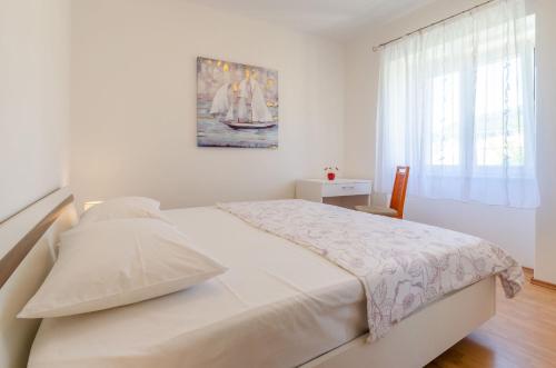 a white bedroom with a bed with a painting on the wall at House Lara in Vela Luka