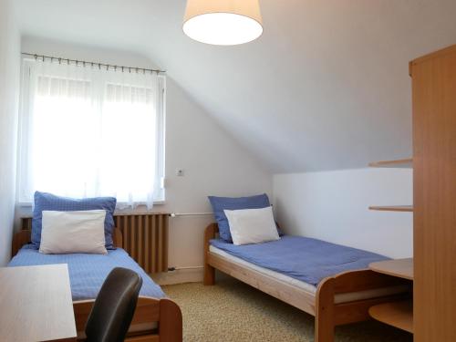 a room with two beds and a table and a window at Herőke Vendégház in Terény